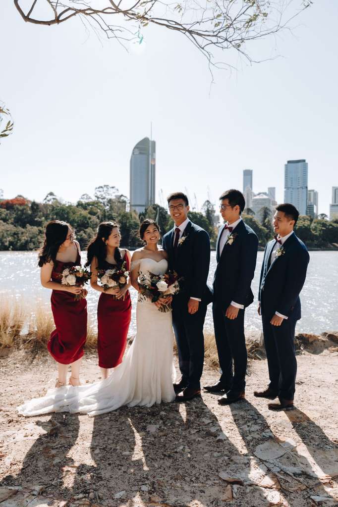 A groom and his groomsmen standing together smiling, wearing elegantly fitted custom wedding suits tailored by West End Tailor.