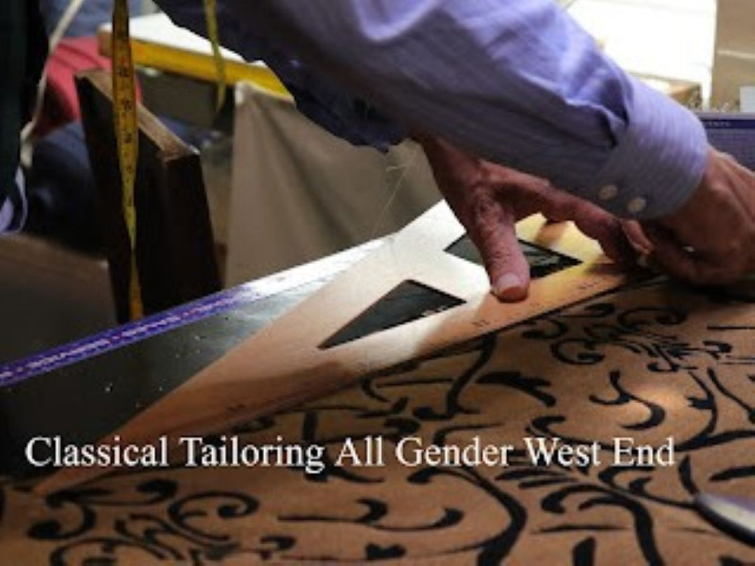 Master tailor hand-drawing a pattern with chalk and ruler on navy suiting fabric at West End Tailor studio.