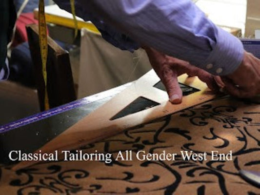 Master tailor hand-drawing a pattern with chalk and ruler on navy suiting fabric at West End Tailor studio.