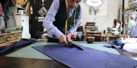 "Master Tailor Feridun Avar cutting high-quality wool fabric on a traditional tailoring bench at West End Tailor studio in Brisbane."